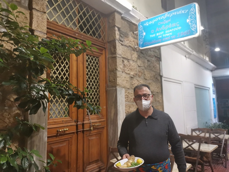Ο Χαράλαμπος Κουγκούλιος κρατώντας ζεστά φρέσκα καλαμαράκια με φόντο την Μυτιλήνη