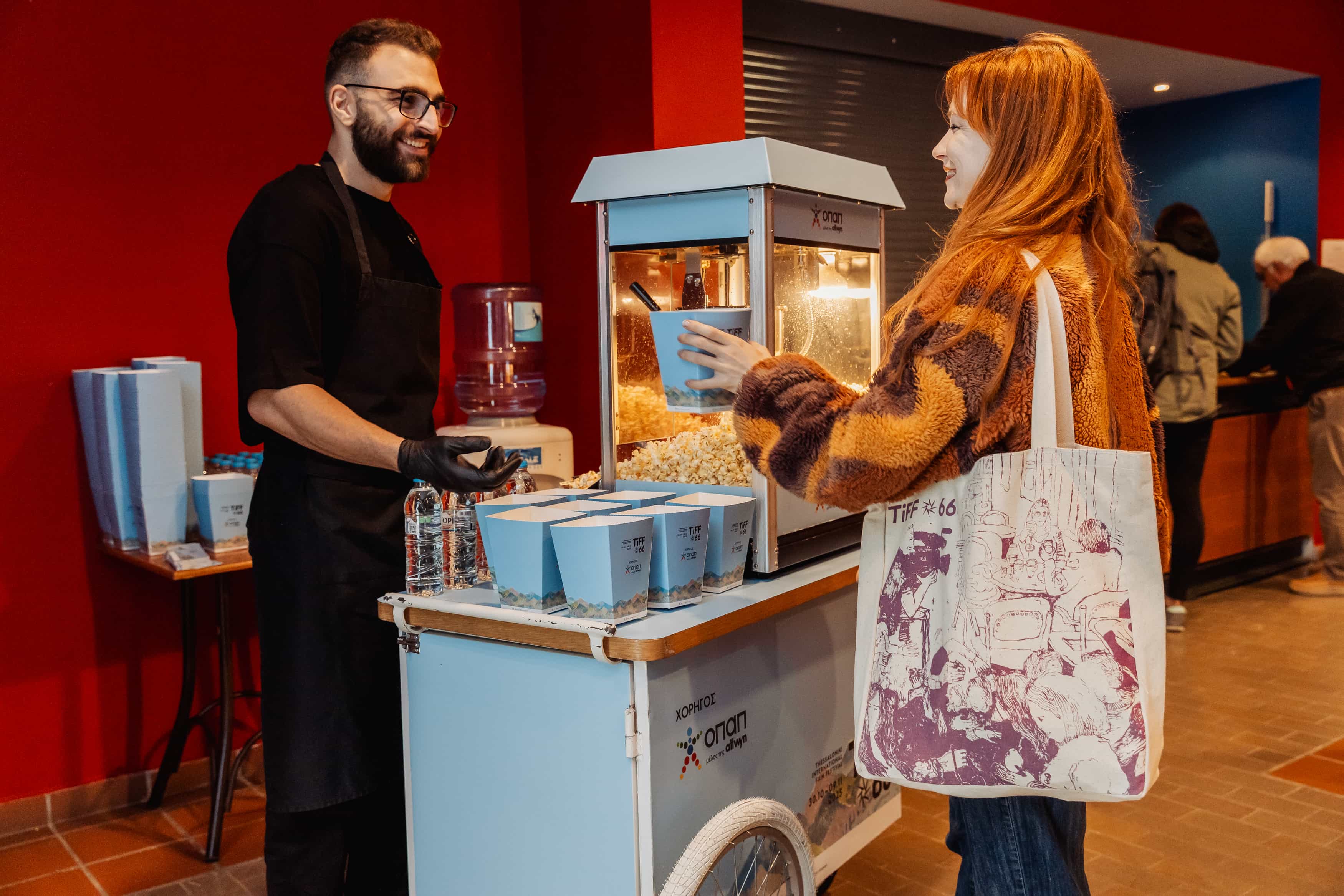 Ο κόσμος παραλαμβάνει popcorn από το station του ΟΠΑΠ για την προβολή της ταινίας Grand Prix